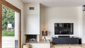 A modern living room with a fireplace, a TV, and a dining area. - Villa 'Maréa' with Sea Views, Wi-Fi, and Air Conditioning (Calonge)