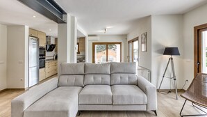 A modern living room with a sectional sofa, a floor lamp, and a view of the kitchen and dining area. - Villa 'Maréa' with Sea Views, Wi-Fi, and Air Conditioning (Calonge)