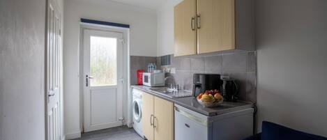 A compact kitchen with a washing machine, a microwave, and a coffee maker.