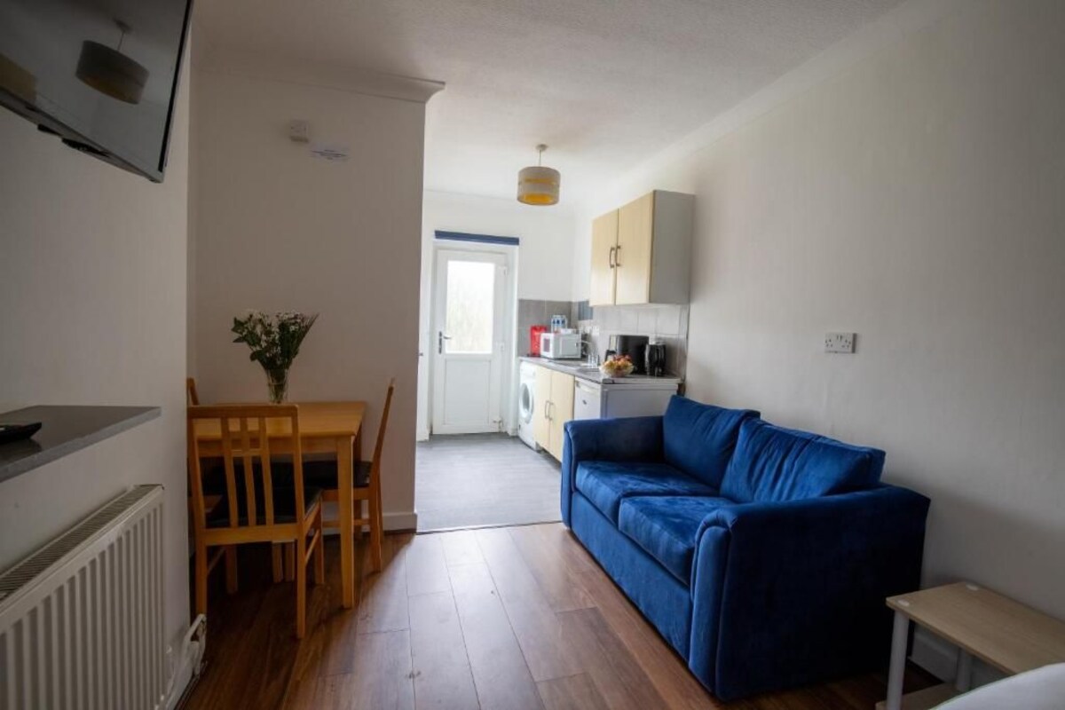A compact living space with a kitchenette, a dining area, and a blue sofa.