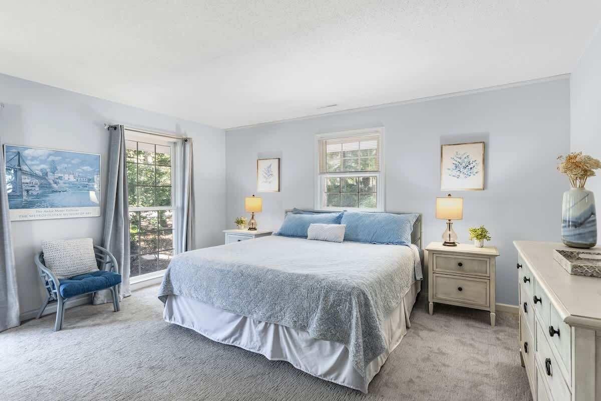 Une chambre à coucher avec un lit, des tables de chevet, une chaise et des œuvres d’art accrochées aux murs.