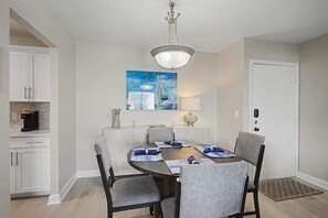 Un coin repas avec une table ronde, des chaises, un tableau, une lampe et une machine à café.