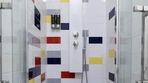 A shower with a glass door, tiled walls with a geometric pattern, and a handheld showerhead.