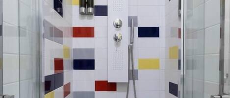 A shower with a glass door, tiled walls with a geometric pattern, and a handheld showerhead.