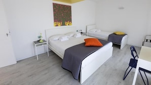 A modern bedroom with two beds, a desk, and a chair.