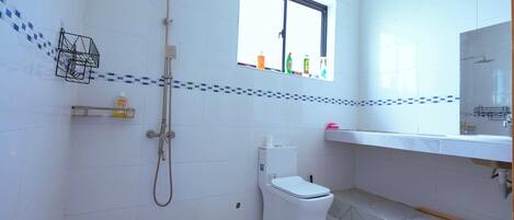 A bathroom with a toilet, shower, and sink.