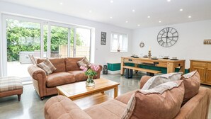 A spacious living room with a brown sofa set, a wooden coffee table, and a dining area with a wooden table and benches. - The Ivy (Norwich)