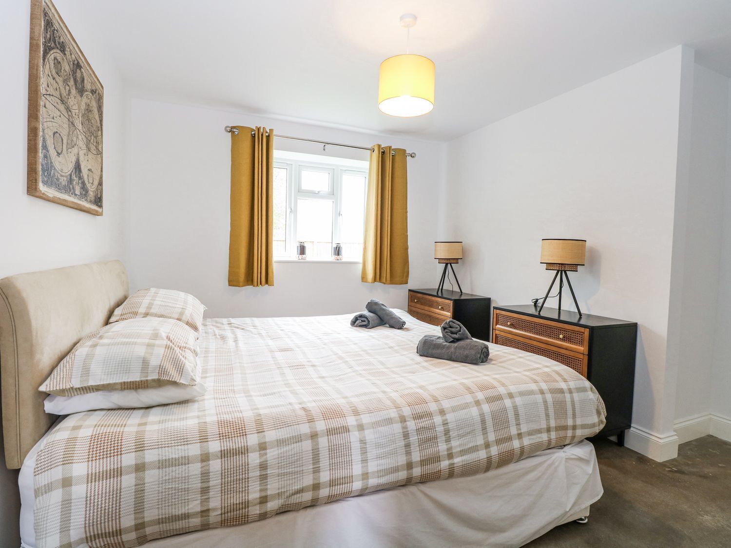 A bedroom with a bed, two bedside tables, a window with curtains, a hanging lamp, and a painting on the wall.