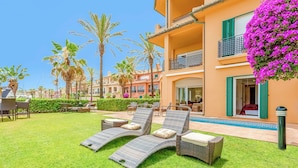 A hotel courtyard with outdoor seating, palm trees, and a pool. - Sotogrande Marina Duo Apartment (Sotogrande)