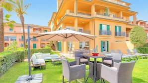 A hotel courtyard with outdoor seating, a covered table, and a pool area. - Sotogrande Marina Duo Apartment (Sotogrande)