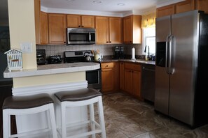 A kitchen with wooden cabinets, a stainless steel refrigerator, a microwave, and a coffee maker. - Newly Listed Summer Weekly Rental - First Floor Duplex - 5 Houses from the Beach (Long Beach)