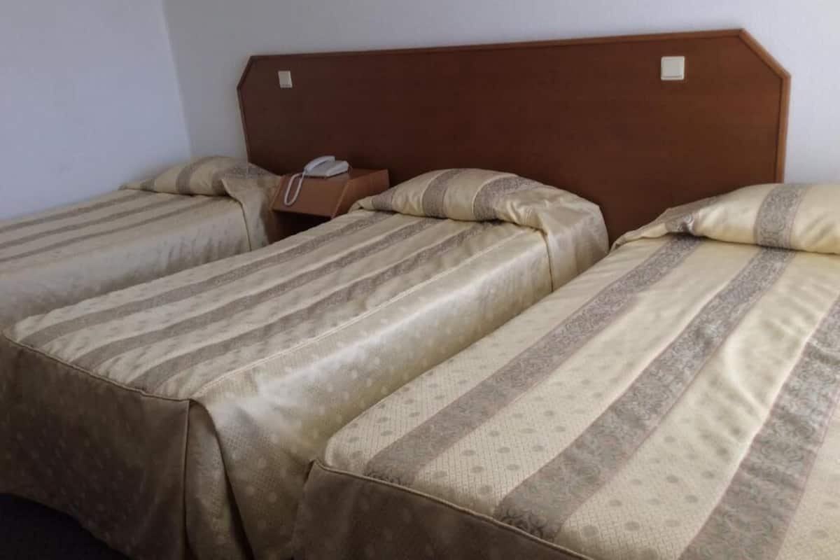 Camera d'albergo con due letti, ciascuno con testiera e comodino.