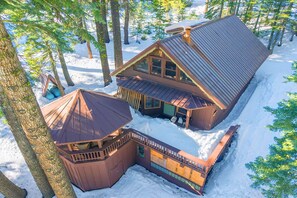 Eine Hütte mit geneigtem Dach, einer Veranda und einer kleinen Terrassenfläche.