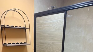 Une salle de bain comprenant des toilettes, un espace douche et une étagère avec un crochet.