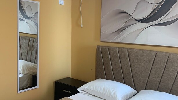 Une chambre d’hôtel avec un lit, une table de chevet, un climatiseur fixé au mur et un grand tableau abstrait.