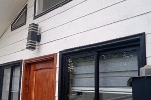 A building with a white exterior, a wooden door, and black-framed windows.