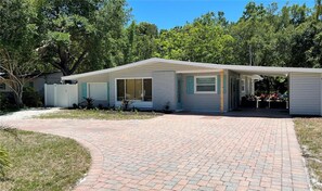 A single-story house with a covered porch, a brick driveway, and a fenced yard. - Private coastal home in downtown Sarasota - large backyard, grill, and firepit! (Sarasota)