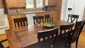 A wooden dining table with six chairs, a coffee maker, and a dish on the table. - Rubicon farmhouse minutes from Erin Hills Golf course, Holy Hill, & Bowery Barn (Rubicon)