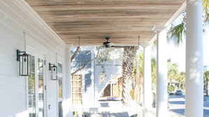 A covered porch with wicker furniture, a ceiling fan, and a view of the street. - Charming Carillon Home + Kid Friendly + Lots of Extras (Panama City Beach)