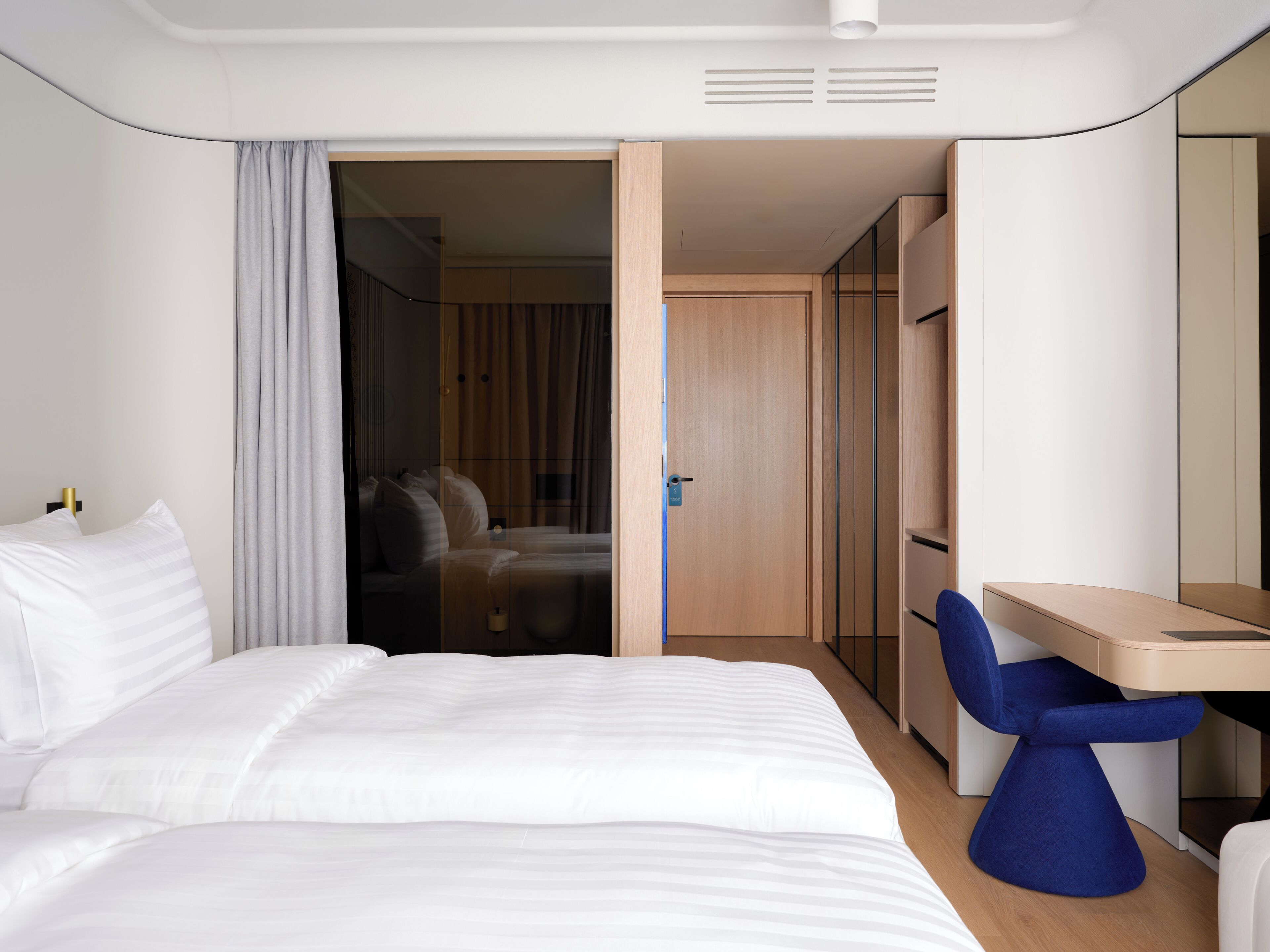 Una habitación de hotel moderna con una cama, un escritorio y una silla.