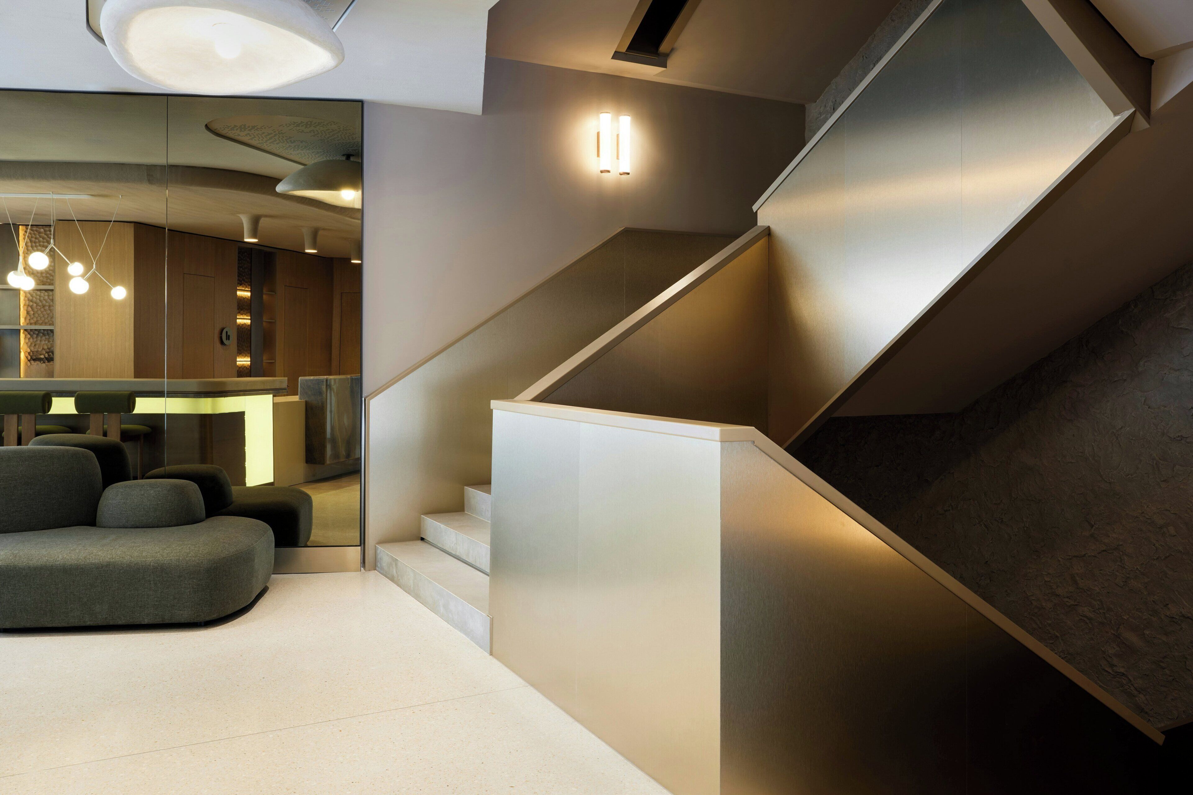 Un intérieur moderne avec un escalier, un coin salon et une cloison en verre.