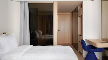 A modern hotel room with a bed, a desk, and a wardrobe.