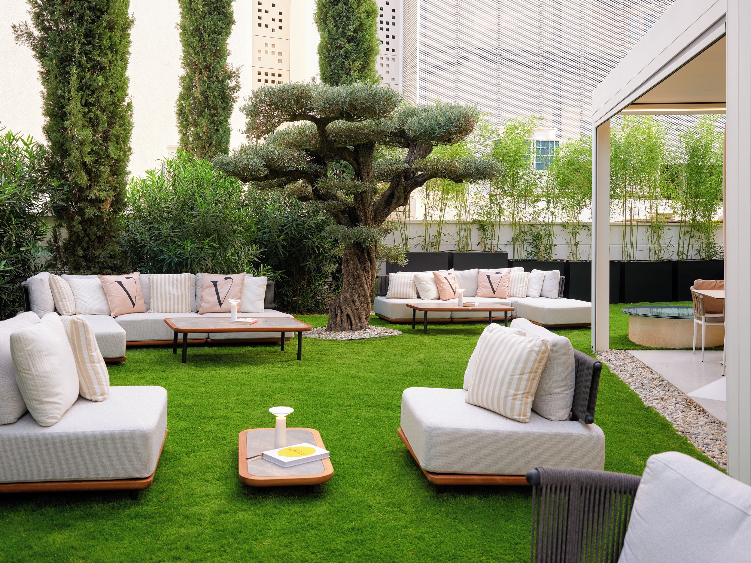 A modern outdoor living space with a sectional sofa, a coffee table, and a large tree.