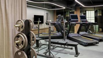 Une salle de sport équipée de tapis de course, de matériel de musculation et d’un mur recouvert de miroirs.