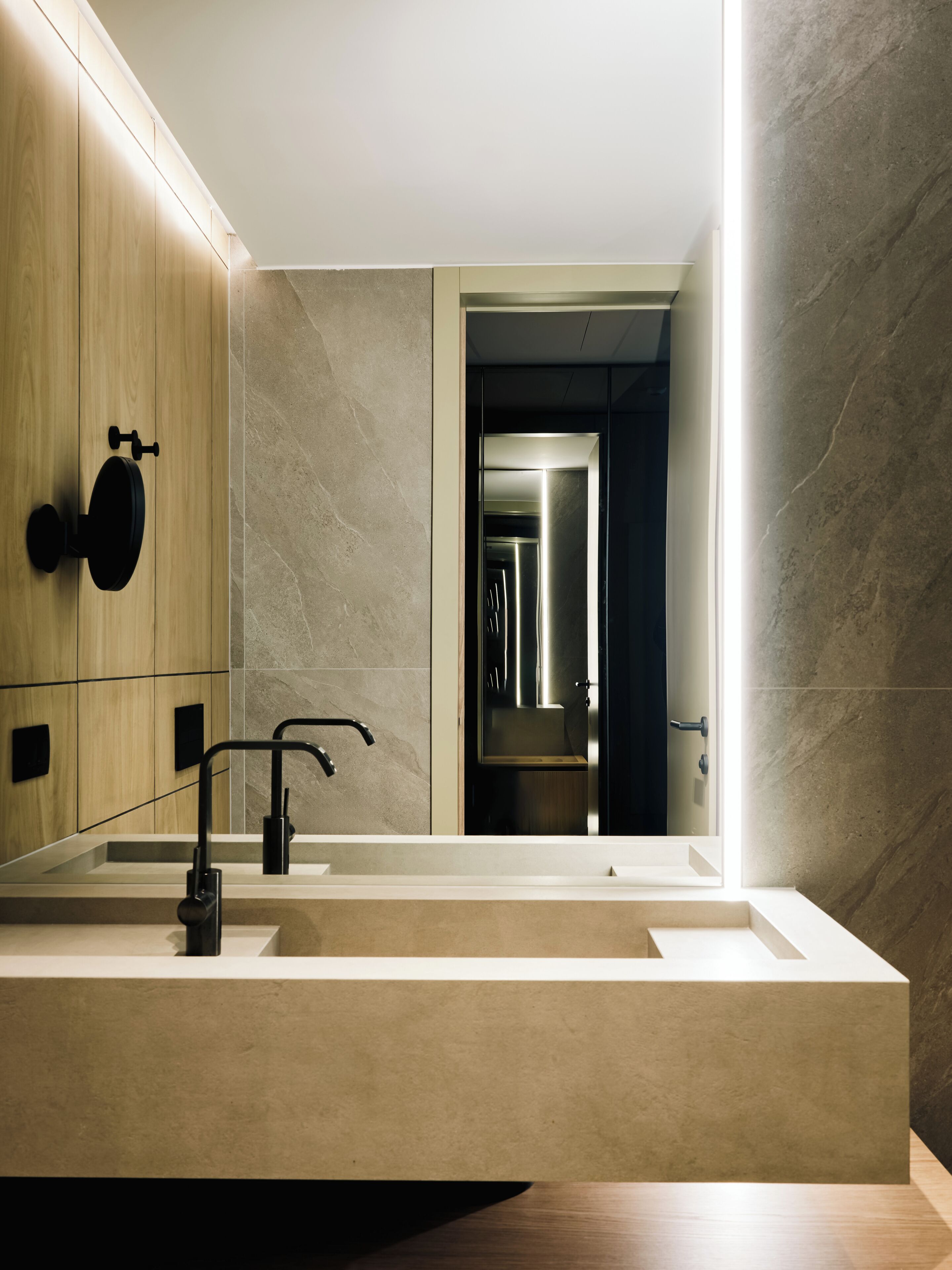 A modern bathroom with a large mirror, a rectangular sink, and a black faucet.