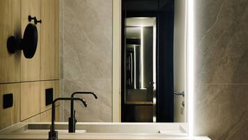 A modern bathroom with a large mirror, a rectangular sink, and a black faucet.