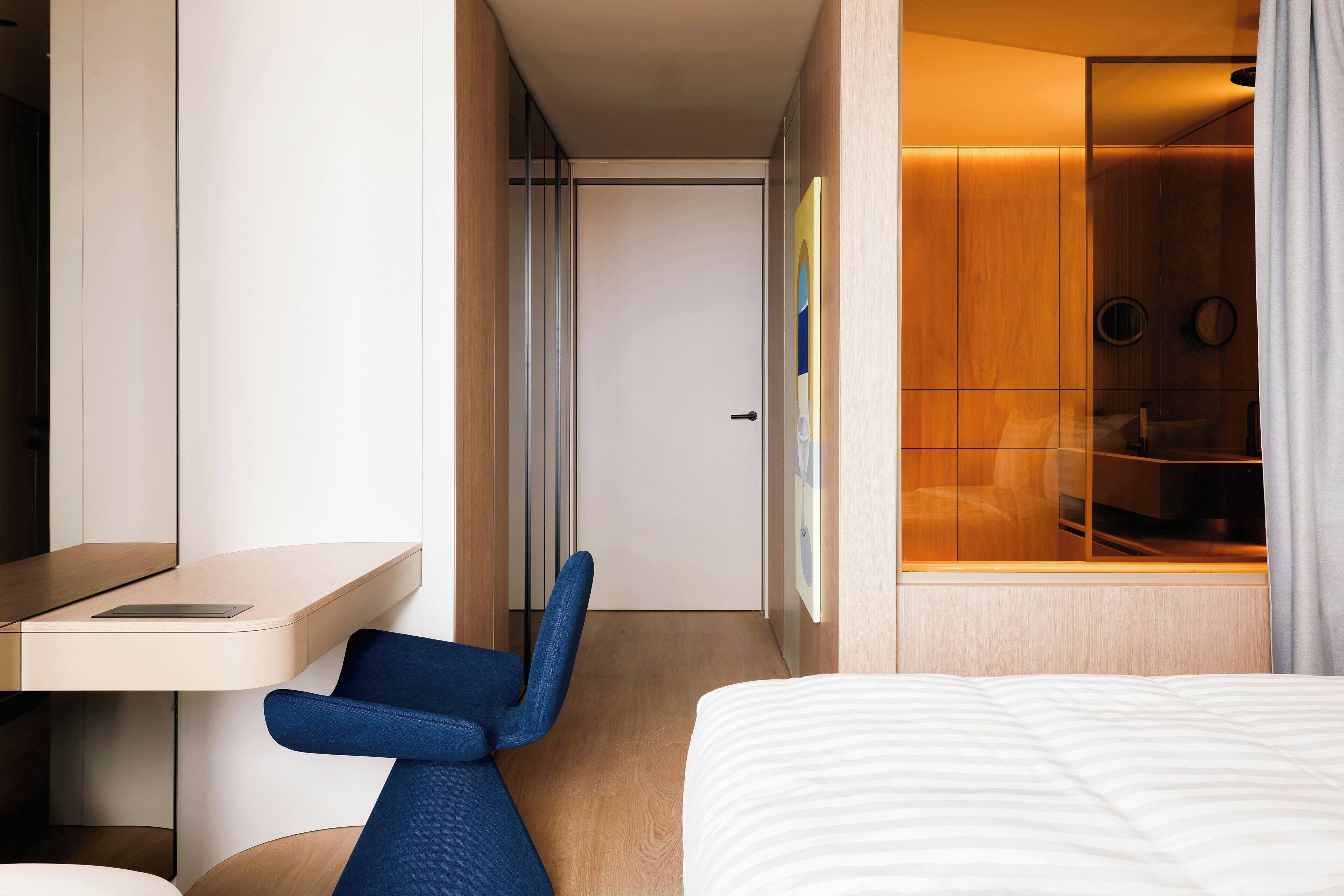 A modern hotel room with a bed, a desk, and a seating area.