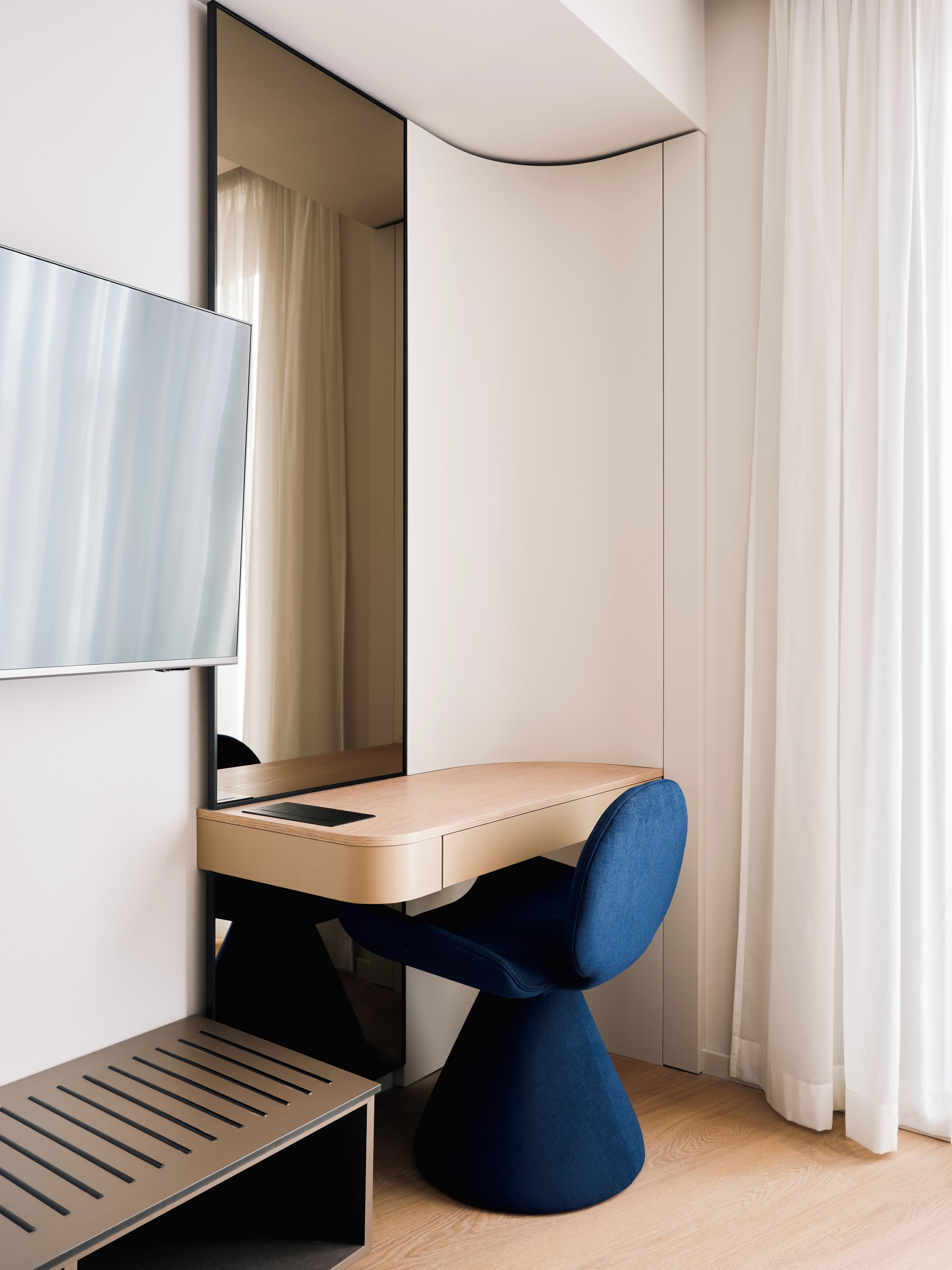 A modern room with a desk, chair, and a large mirror.