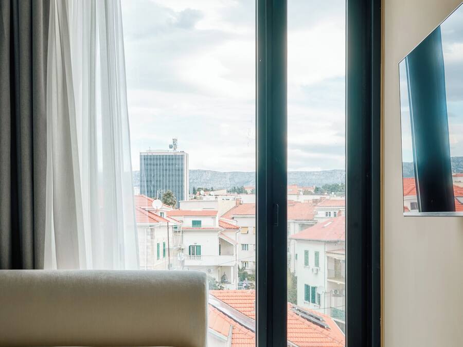 Una habitación con un ventanal grande, un sofá y vistas a edificios.