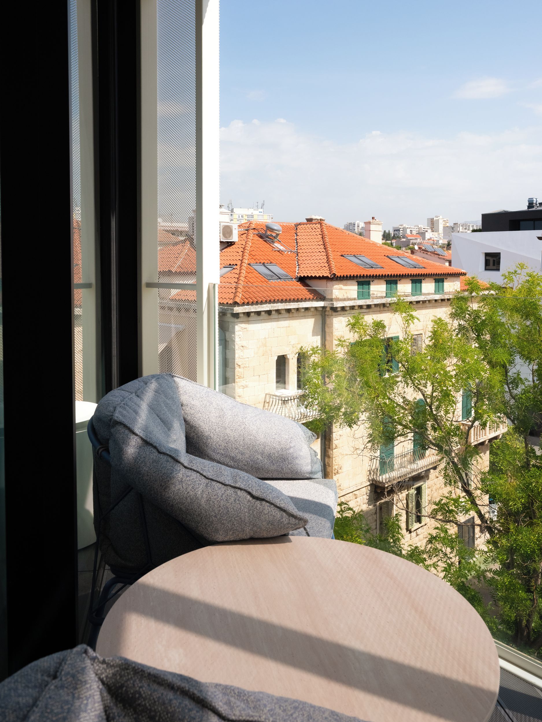 Ein Zimmer mit Blick auf Gebäude und einen Baum.