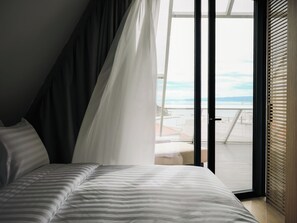 A bedroom with a bed, a view of the beach, and a sliding glass door. - Boutique Hotel Venturo, a Member of Design Hotels Adults only (Split)