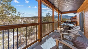 A wooden deck with a metal railing, outdoor seating, and a table with chairs.