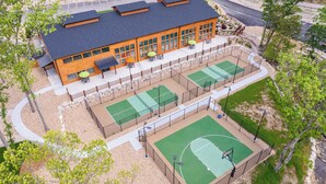 A multi-story building with a sports court, outdoor seating, and a parking lot.
