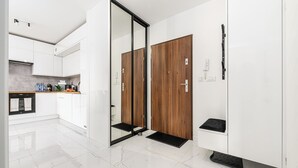 A modern kitchen with white cabinets, a black countertop, and a wooden door. - Lumina 3-rooms apart with balcony (Łódź)