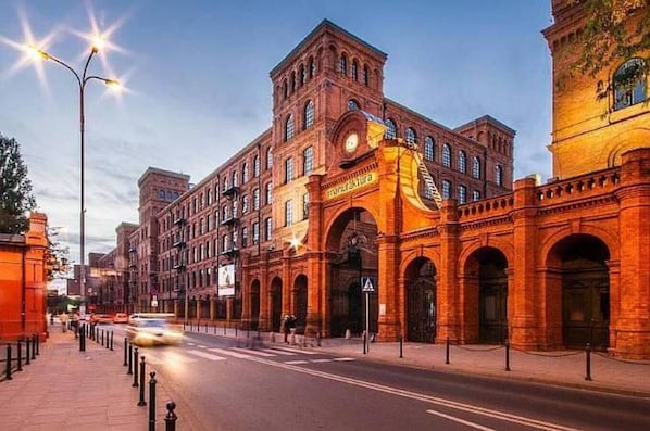 A historic building with arched windows and a prominent clock tower. - Lumina 3-rooms apart with balcony (Łódź)