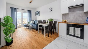 A modern apartment with a dining area, kitchen, and a large window with curtains. - Lumina 3-rooms apart with balcony (Łódź)