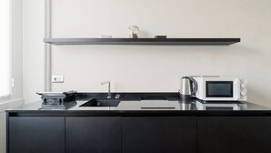 A modern kitchen with a black countertop, a stainless steel sink, a white microwave, and a small shelf above the counter. - GuestHost - A cozy and bright apartment of approximately 35 square meters, perfect for two people, located on the second floor of a building with an elevator (NOT accessible to disabled guests).The property is located in a central area of ​​Milan and (Milan)