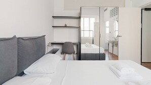 A modern hotel room with a large bed, a desk, a chair, a mirror, and a bathroom visible through an open door. - GuestHost - A cozy and bright apartment of approximately 35 square meters, perfect for two people, located on the second floor of a building with an elevator (NOT accessible to disabled guests).The property is located in a central area of ​​Milan and (Milan)