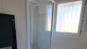 A bathroom with a glass shower enclosure, a white sink, and a television mounted on the wall. - QUIRI45-40000 (Mont-de-Marsan)