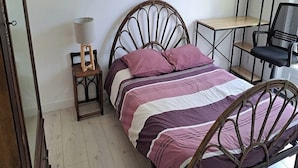 A bedroom with a bed, a nightstand, a lamp, a chair, and a small table. - QUIRI45-40000 (Mont-de-Marsan)