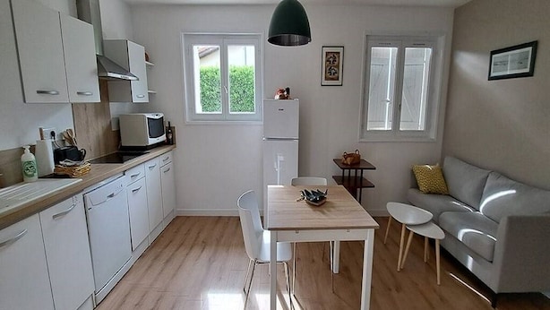 A compact kitchen with white cabinets, a microwave, and a refrigerator. There is a dining table with chairs, a sofa, and a small table with two chairs. - QUIRI45-40000 (Mont-de-Marsan)