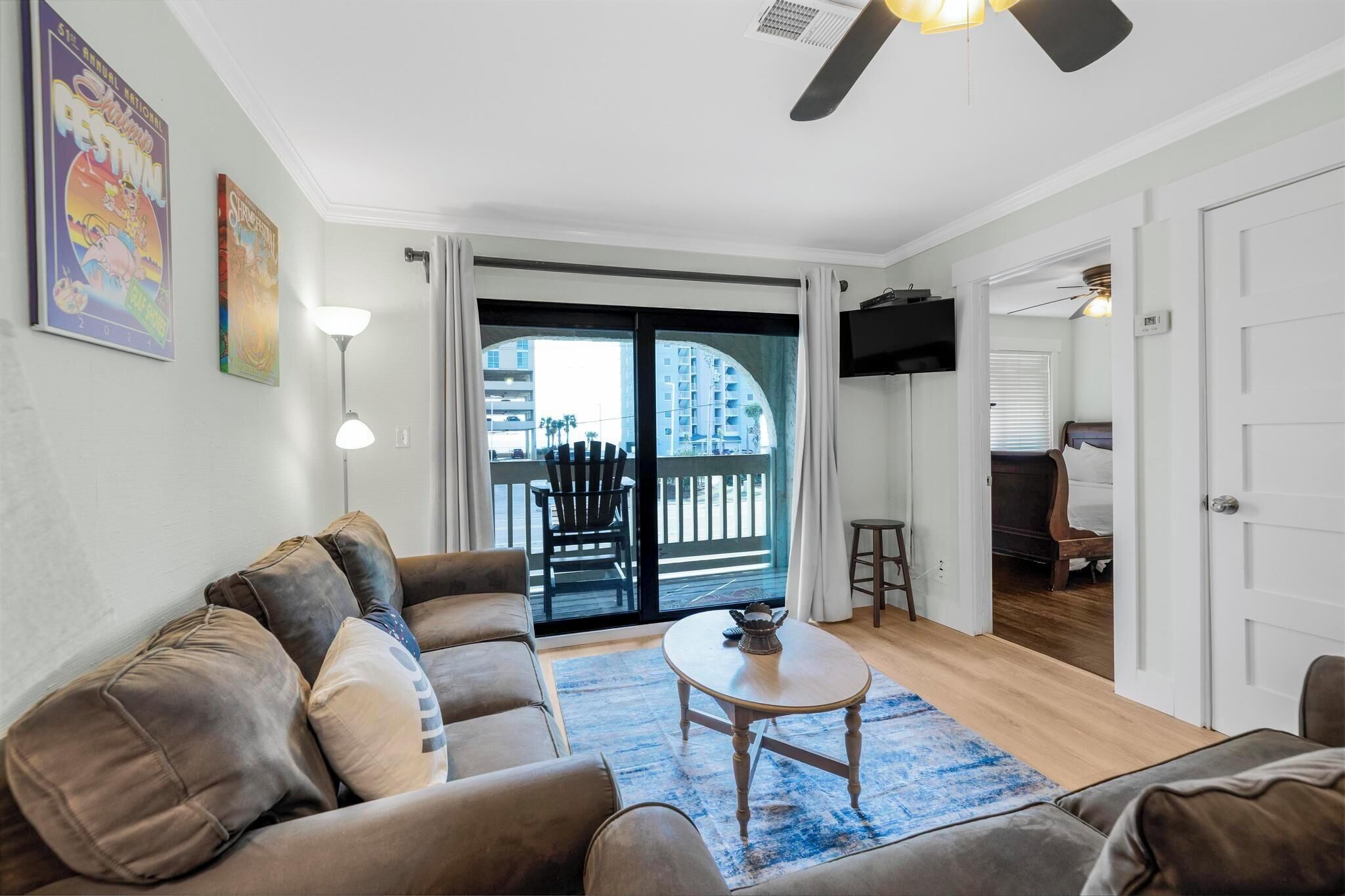 A living room with a sofa, a coffee table, and a view of a balcony with a chair.