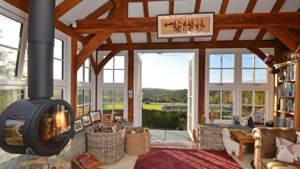 Ein gemütliches Zimmer mit Kamin aus Stein, einem großen Fenster und Blick auf die Landschaft.