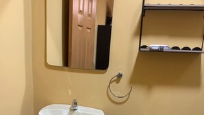 Une salle de bain avec un lavabo sur colonne, des toilettes et un miroir au-dessus du lavabo.