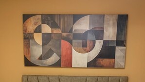 Un lit avec une tête de lit et un grand tableau abstrait accroché au-dessus.