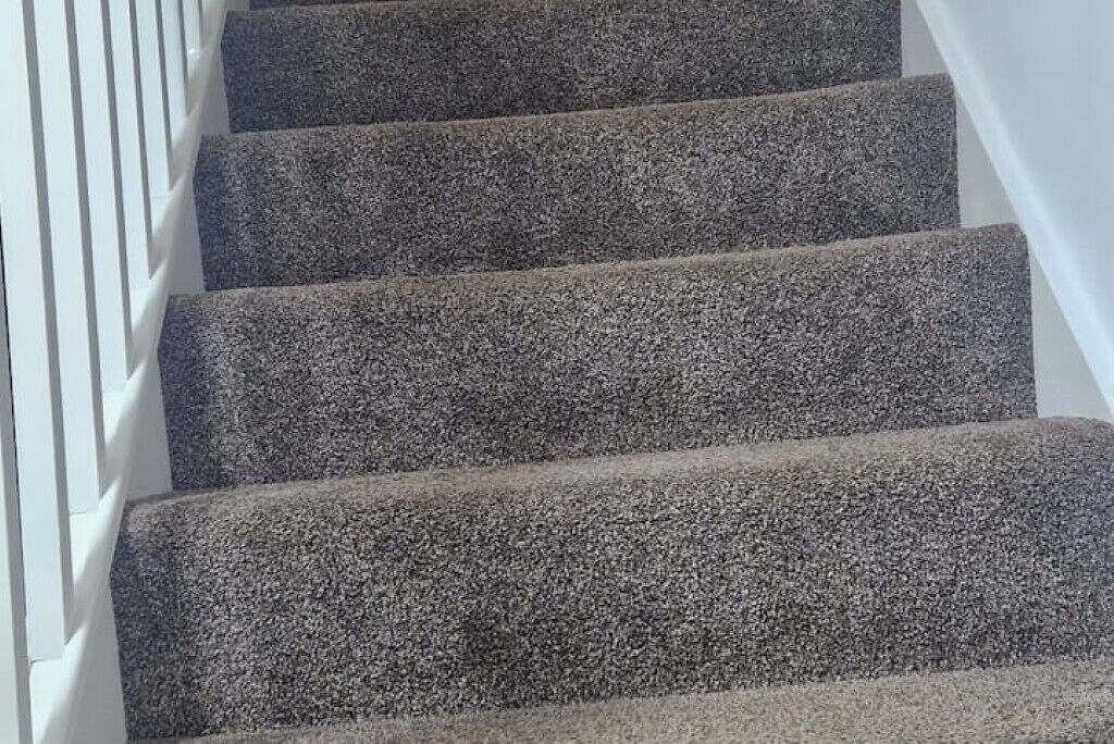 A staircase with a textured carpet.